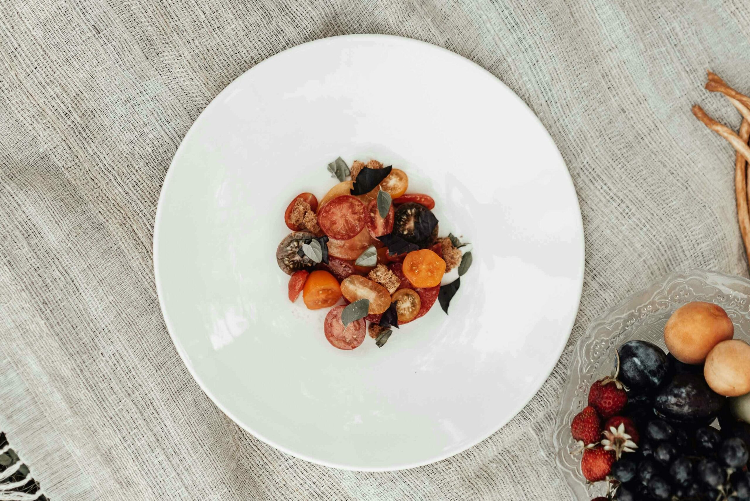 Bowl of peach and tomato salad in middle of table.